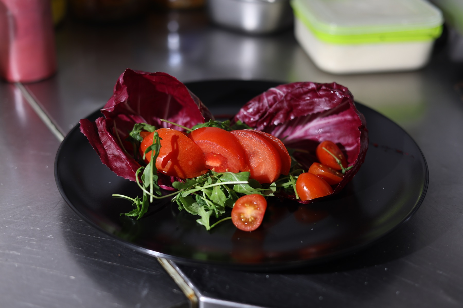 Tomatoes and greens prepared on a black plate